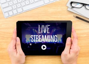 Hand holding tablet with Live Streaming word on wood table ,Internet marketing concept..